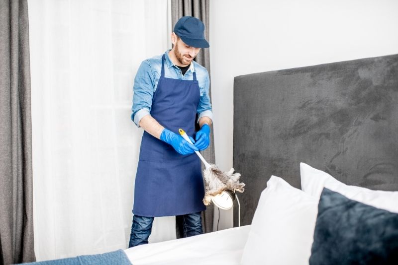 Man dusting a night light lamp during an end of lease clean