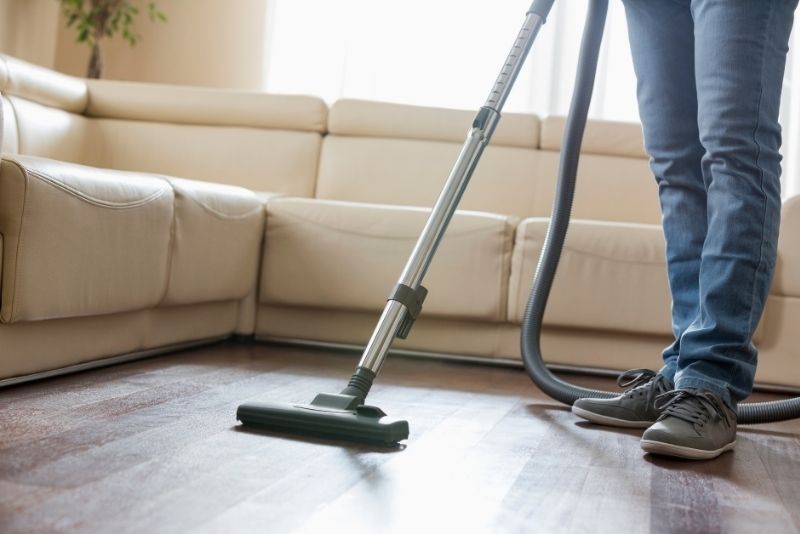 Person vacuuming a wooden floor during a deep clean