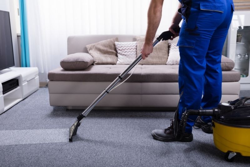 Cleaner using a carpet extractor machine on a living room carpet