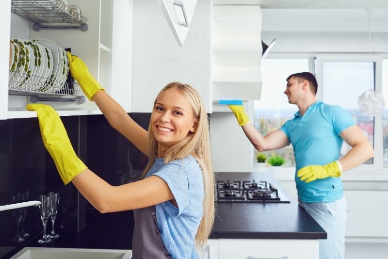 Two cleaners wiping kitchen cabinets and a rangehood in Port Douglas