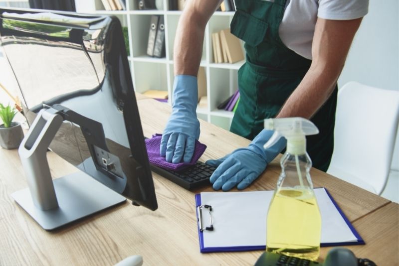 Cleaner wiping down a desk and keyboard during an office clean in Cairns Central