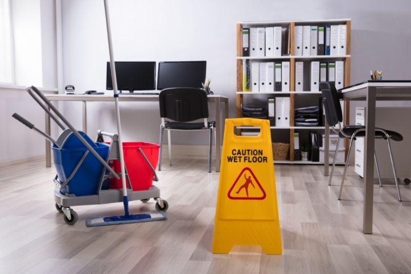Mop cart and wet floor caution sign set up in an office during a clean